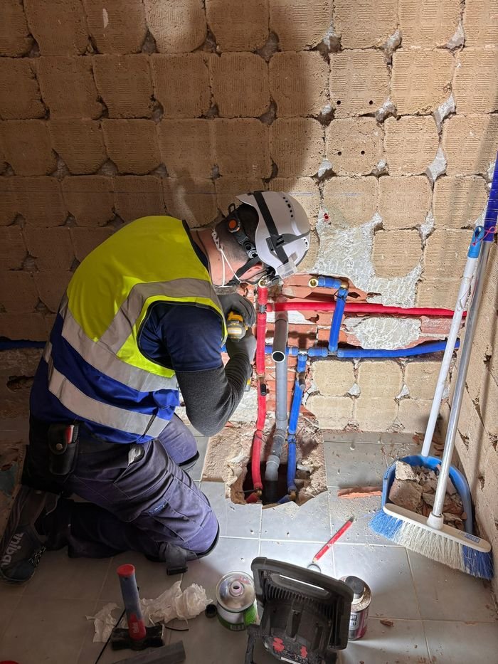 Fontanero de AV Mantenimiento Integral instalando tuberías de agua fría y caliente en una pared picada